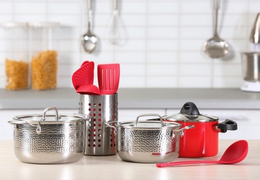 Photo of Set of clean cookware and utensils on table in kitchen