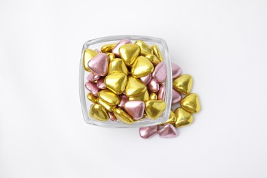 Photo of Glass bowl and many delicious heart shaped candies on white background, flat lay