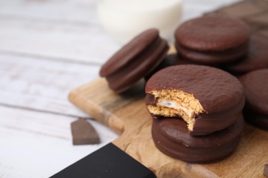 Photo of Tasty choco pies on white wooden table, closeup. Space for text