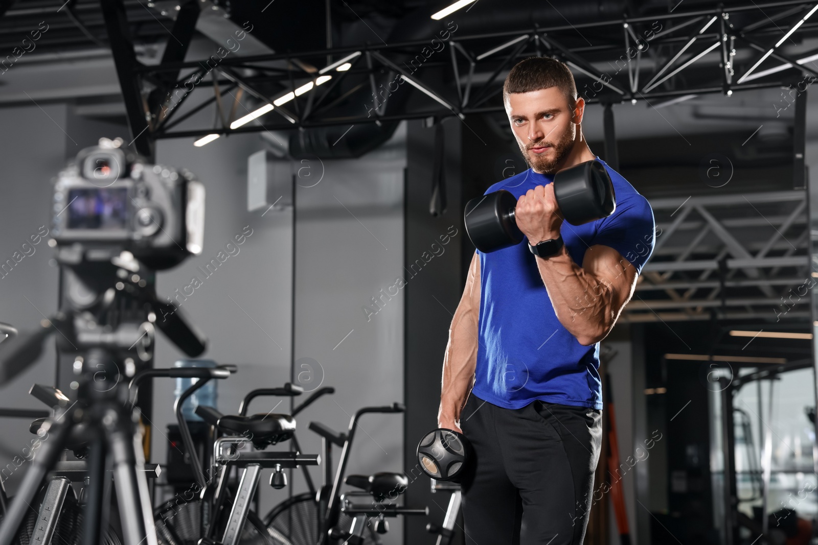 Photo of Man recording workout on camera at gym. Online fitness trainer