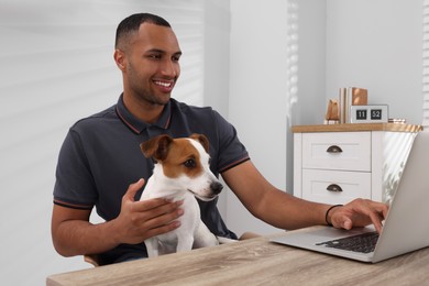 Photo of Young man with Jack Russell Terrier working at desk in home office