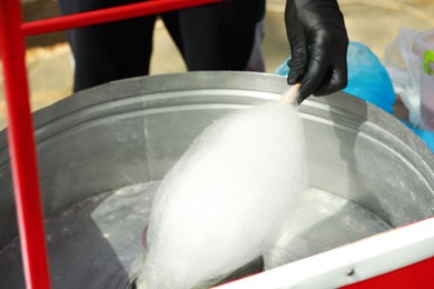 Photo of Man making cotton candy with machine outdoors, closeup