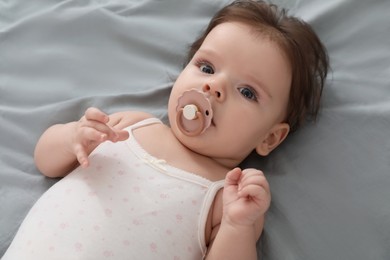 Photo of Cute little baby with pacifier on bed