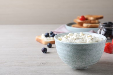 Photo of Tasty cream cheese and fresh berries on white wooden table. Space for text