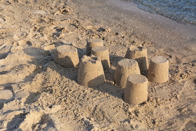 Photo of View of beach with little sand figures near sea on sunny summer day