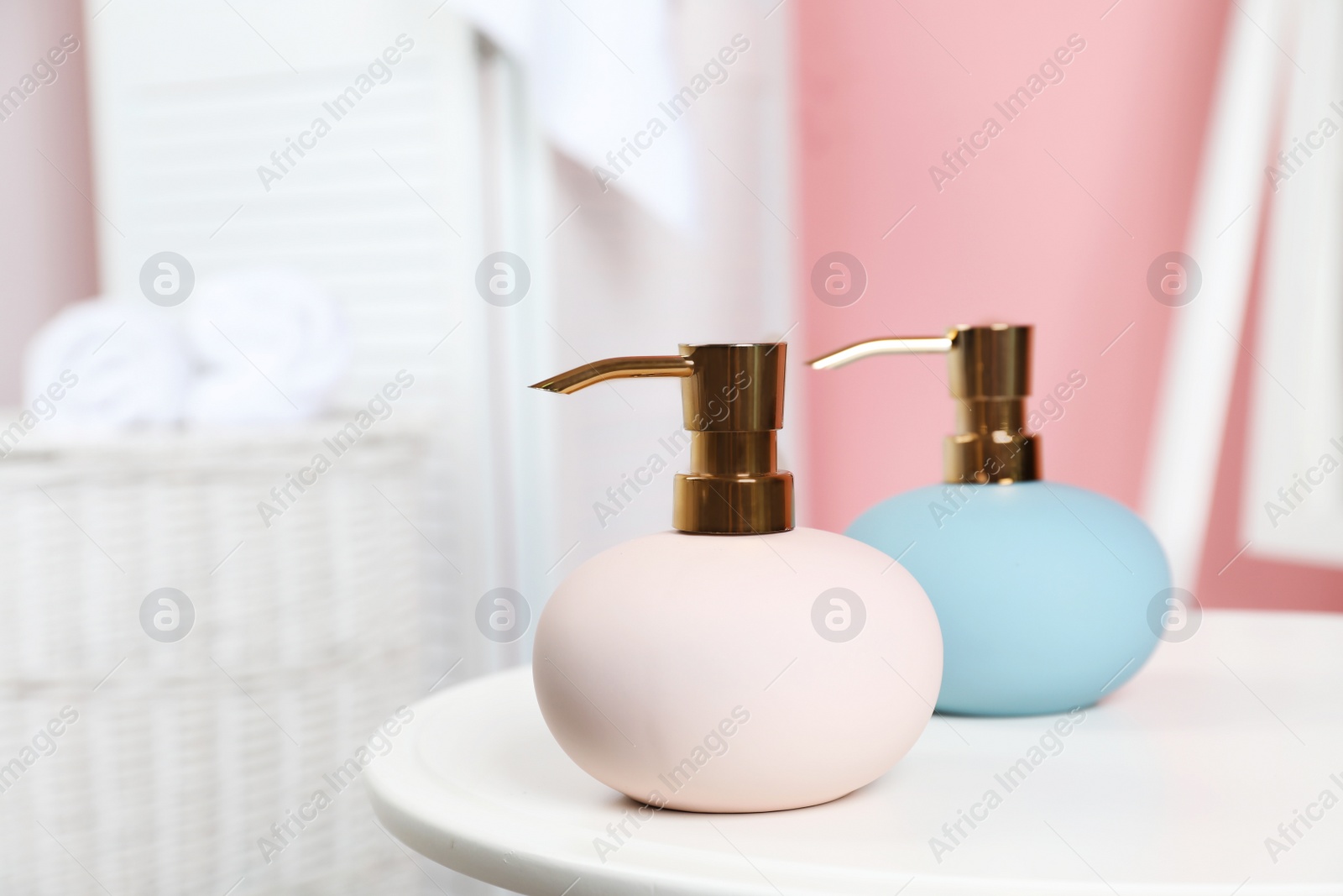 Photo of Stylish soap dispensers on table against blurred background. Space for text