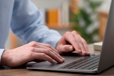 Photo of E-learning. Man using laptop during online lesson at table indoors, closeup