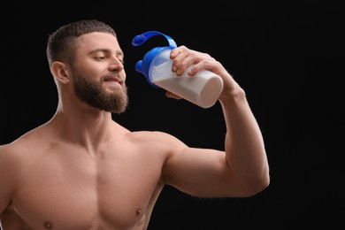 Photo of Young man with muscular body drinking protein shake on black background