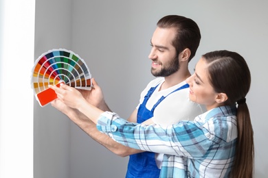 Photo of Male decorator and young woman with color palette indoors