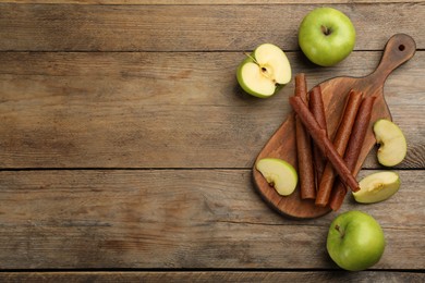 Photo of Delicious fruit leather rolls and apples on wooden table, flat lay. Space for text