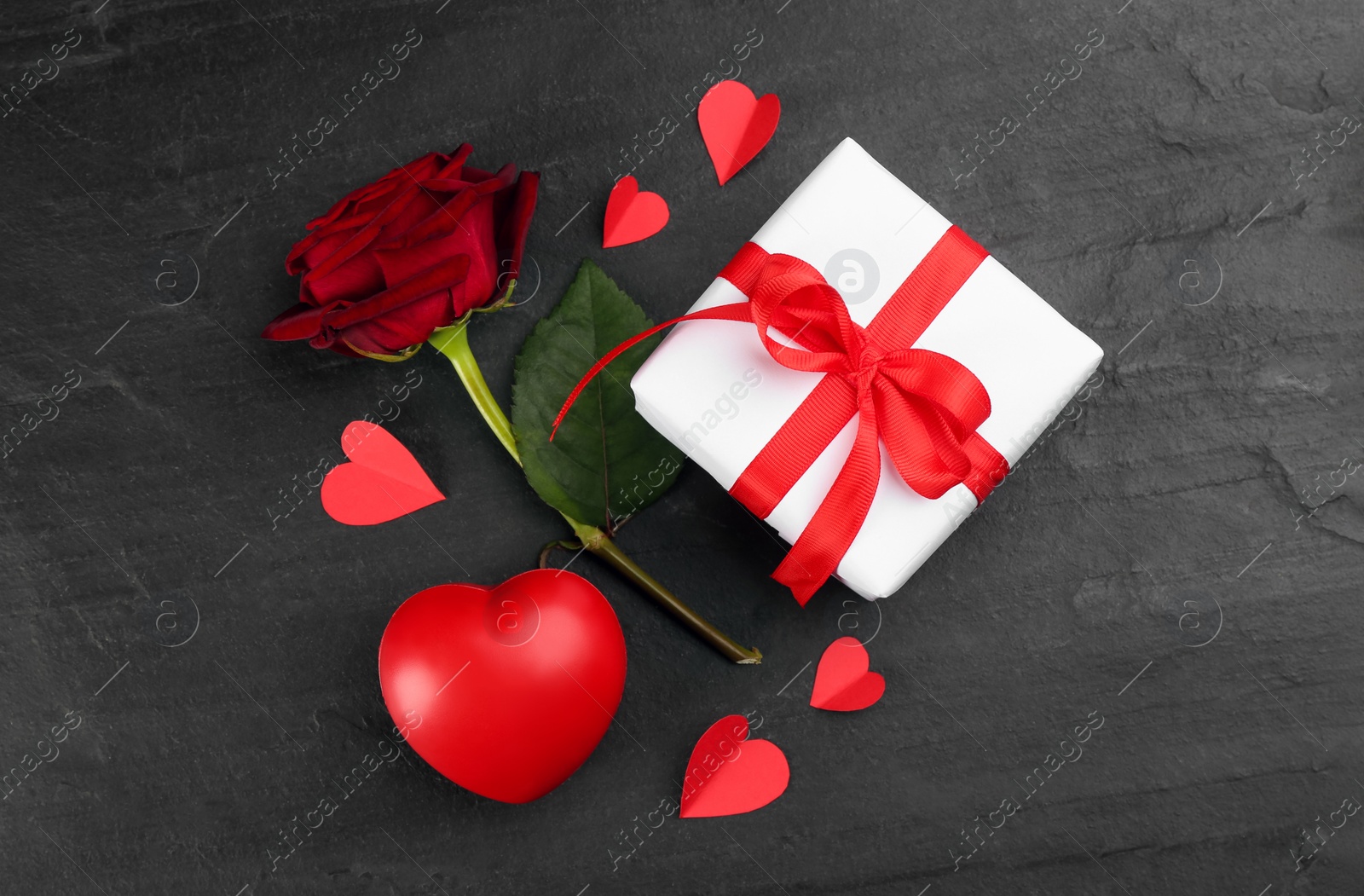 Photo of Gift box, rose and hearts on black background, flat lay. Valentine's Day celebration