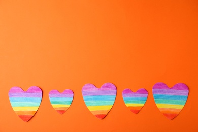 Photo of Top view of rainbow hearts on color background, space for text. Gay symbol