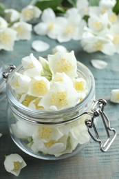 Photo of Beautiful jasmine flowers in glass jar on blue wooden table