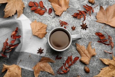 Photo of Flat lay composition with cup of hot drink and autumn leaves on grey table. Cozy atmosphere