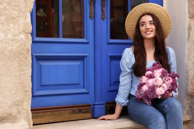 Photo of Beautiful woman with bouquet of spring flowers near building outdoors, space for text