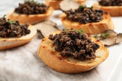 Photo of Delicious bruschettas with truffle sauce and thyme on white table, closeup