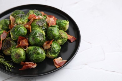 Photo of Delicious roasted Brussels sprouts, bacon and rosemary on white textured table, closeup. Space for text