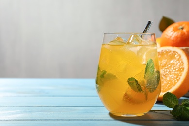 Photo of Delicious orange soda water on light blue wooden table. Space for text