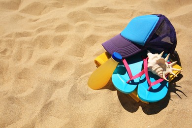 Photo of Cap, flip flops, seashell and refreshing drink on beach, space for text