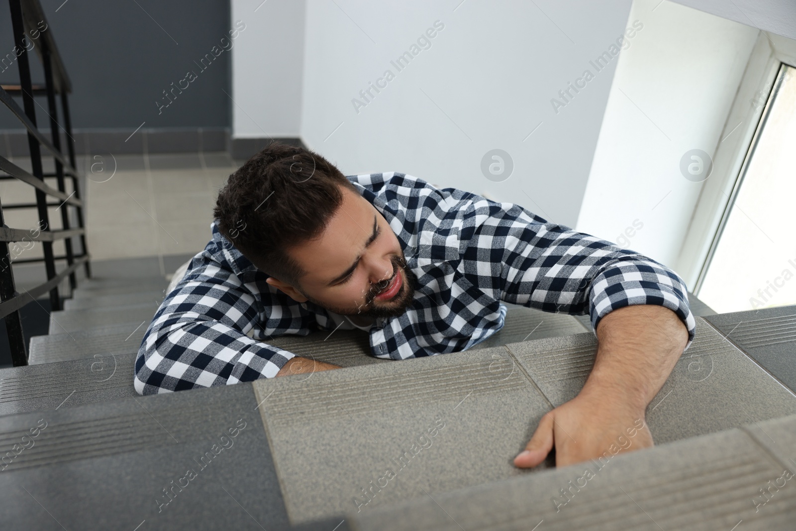 Photo of Man fallen down stairs suffering from pain indoors