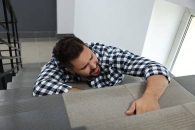 Photo of Man fallen down stairs suffering from pain indoors