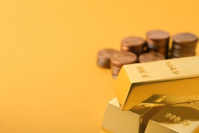 Photo of Shiny gold bars and coins on color background. Space for text