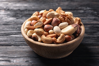 Photo of Bowl with organic mixed nuts on wooden table