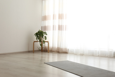 Photo of Unrolled grey yoga mat on floor in room. Space for text