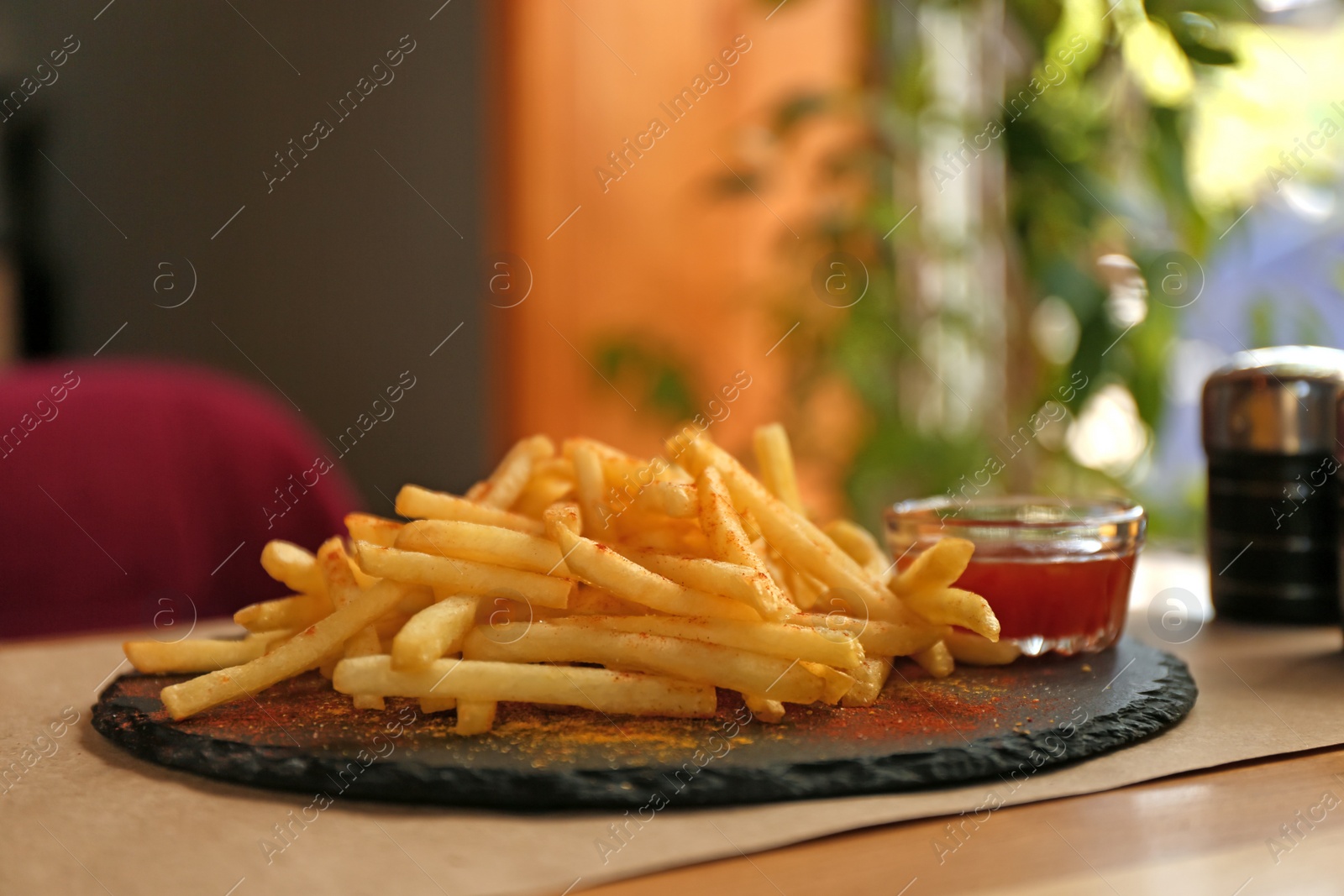 Photo of Delicious hot french fries with red sauce served on table