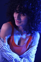 Photo of Beautiful young woman posing on color background in neon lights, closeup