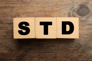 Photo of Abbreviation STD made with cubes on wooden table, flat lay