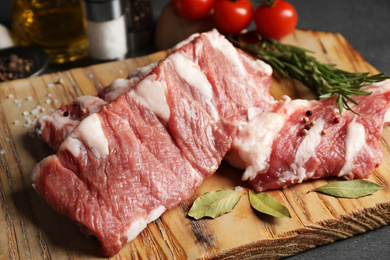 Photo of Raw ribs with bay leaves and pepper on wooden board, closeup