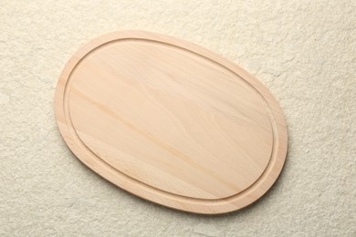 Photo of Wooden cutting board on beige table, top view. Space for text