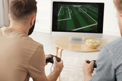 Photo of Young men playing video games at home