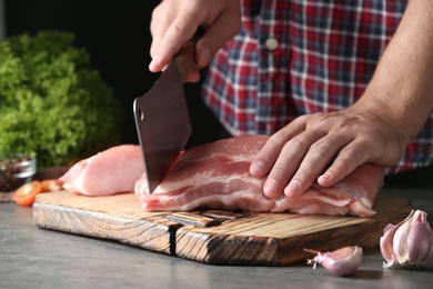 Photo of Man cutting fresh raw meat on table, closeup