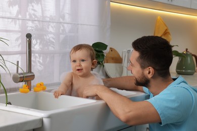Photo of Father washing his little baby in sink at home