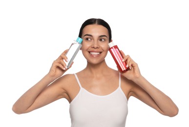 Young woman with bottles of micellar water on white background