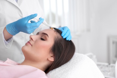 Photo of Young woman with hair loss problem receiving injection in salon