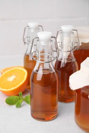Photo of Tasty kombucha, orange and mint on white table