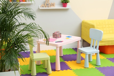 Photo of Stylish playroom interior with table, chairs and sofa