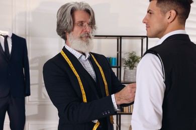 Photo of Professional tailor working with client in atelier