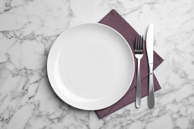 Photo of Stylish ceramic plate, napkin and cutlery on marble background, flat lay