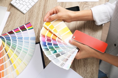 Photo of Woman with color palette samples at table, closeup