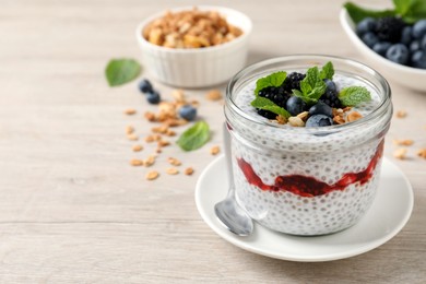 Photo of Delicious chia pudding with berries and granola on wooden table. Space for text