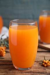Photo of Sea buckthorn juice and fresh berries on wooden table, closeup