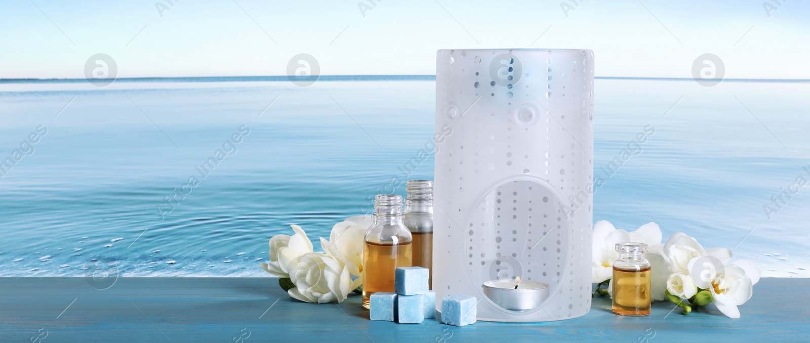 Image of Composition with aroma lamp on blue wooden table near sea , space for text. Banner design