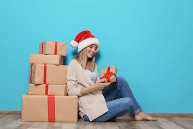 Photo of Young woman with Christmas gifts near color wall