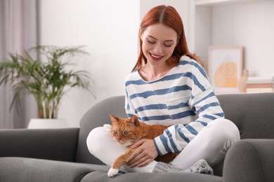 Photo of Happy woman with her cute cat on sofa at home