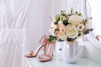 Photo of Beautiful wedding bouquet and shoes on dressing table indoors