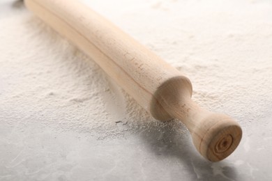 Photo of Rolling pin and flour on grey marble table, closeup